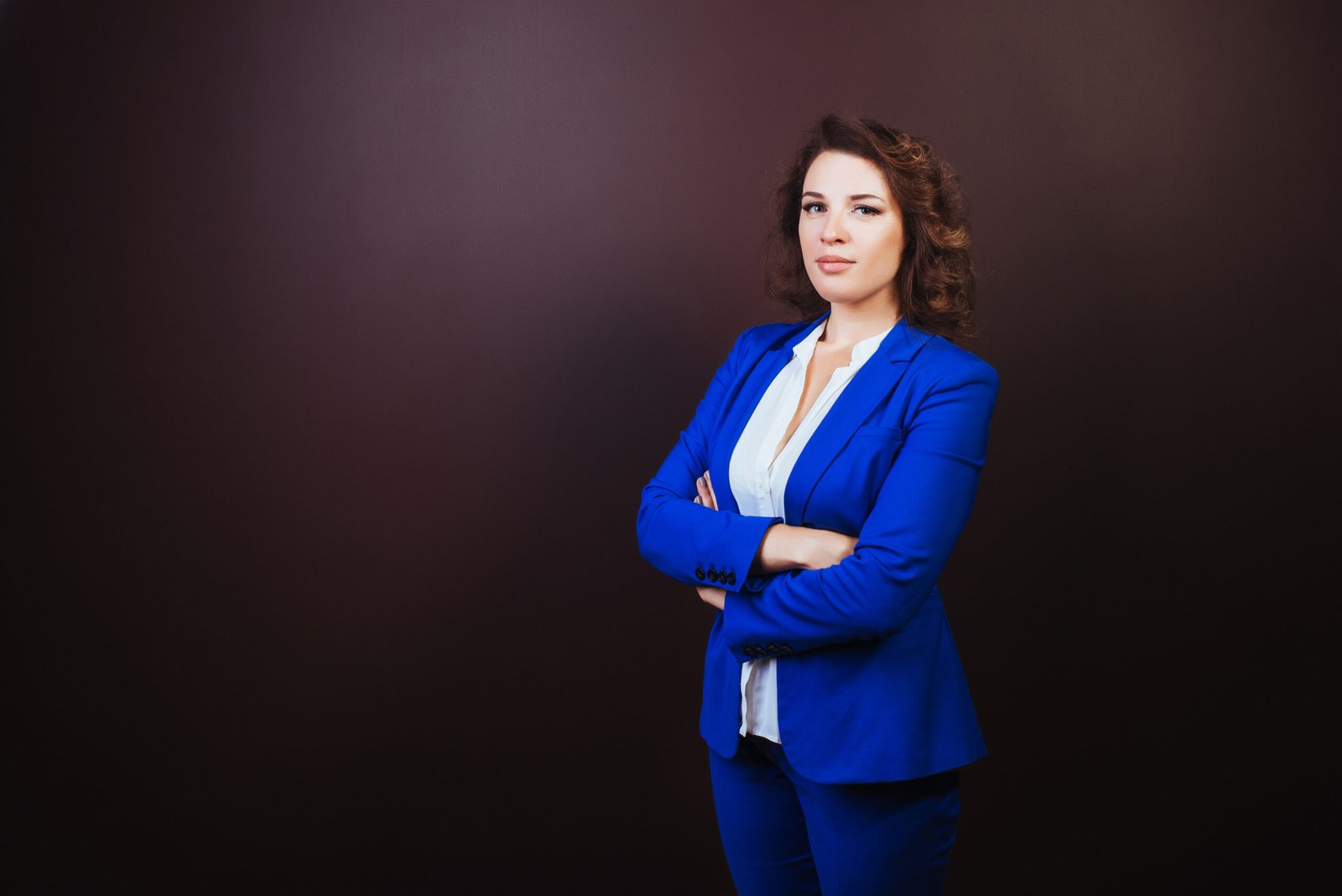 Confident business woman standing in a blue suit with hands clasped. Business concept